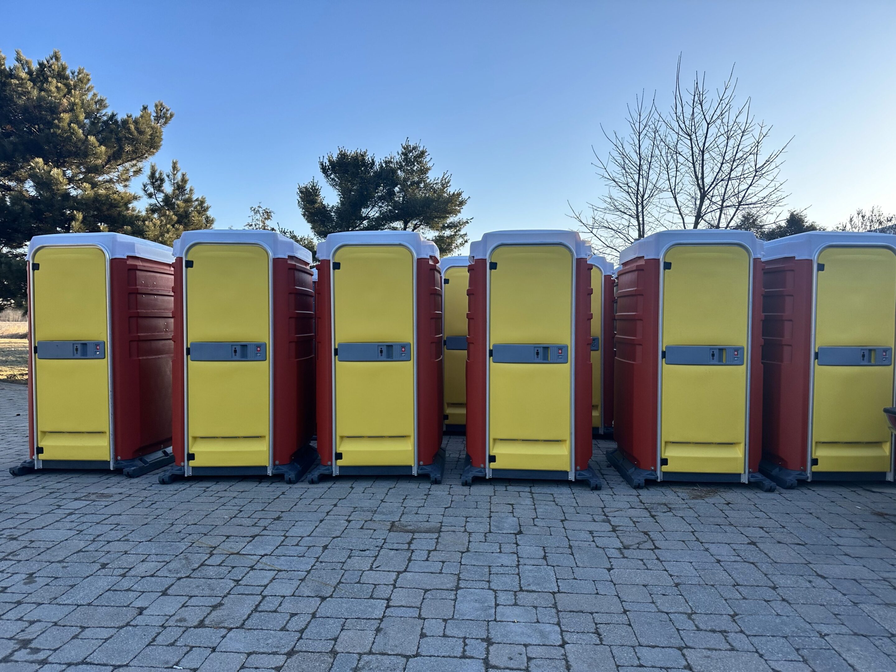 A row of portable toilets on the side of a road.