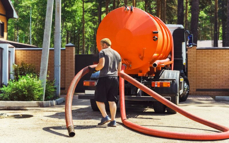 GettyImages-2168908274 A man holding onto a hose from the back of a truck.