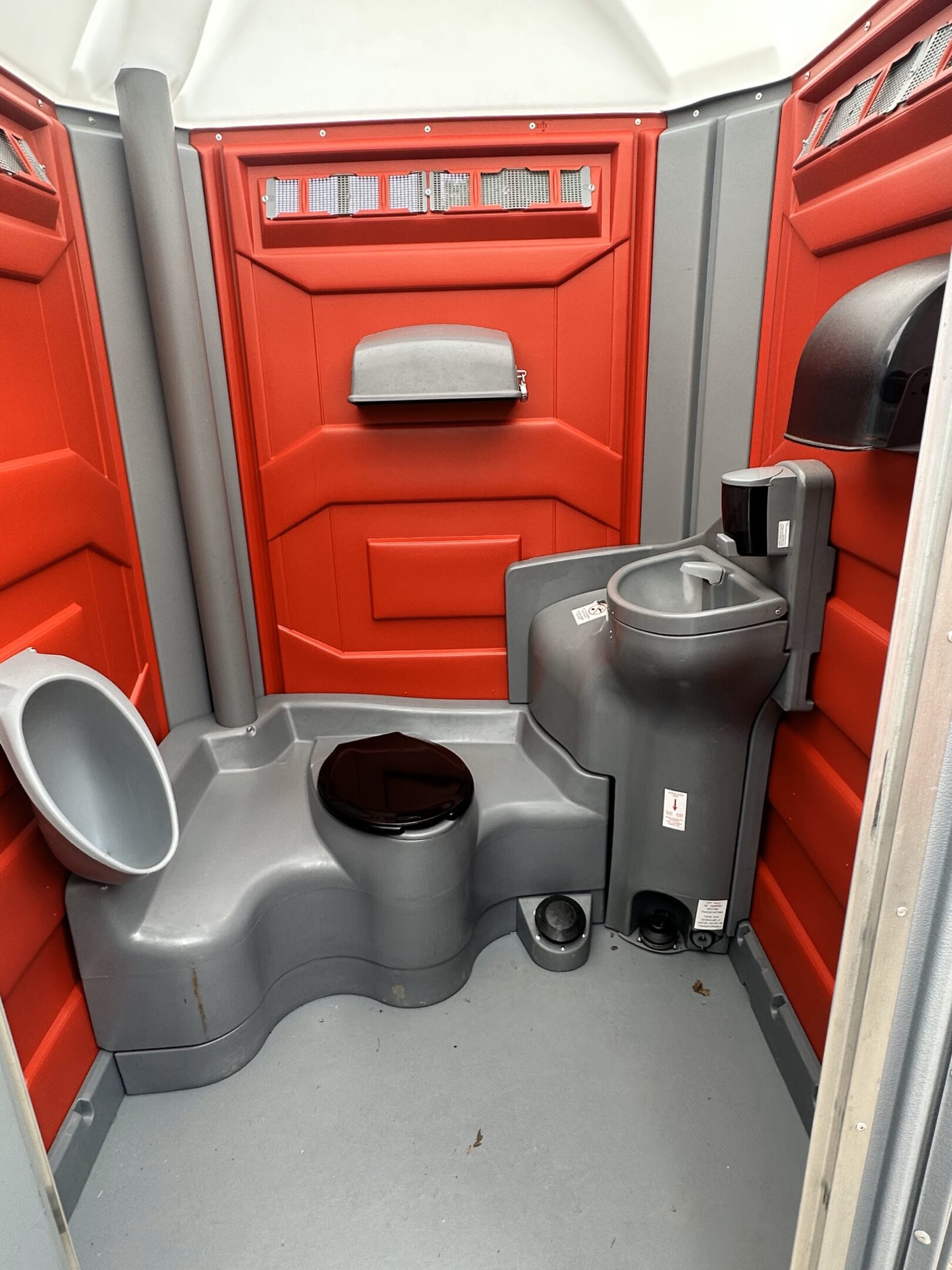A small bathroom with red walls and grey toilet.
