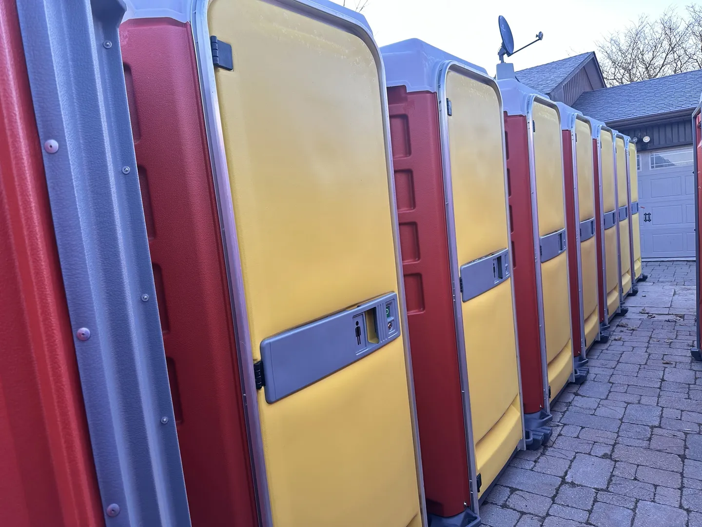 A row of portable toilets lined up on the side of a road.